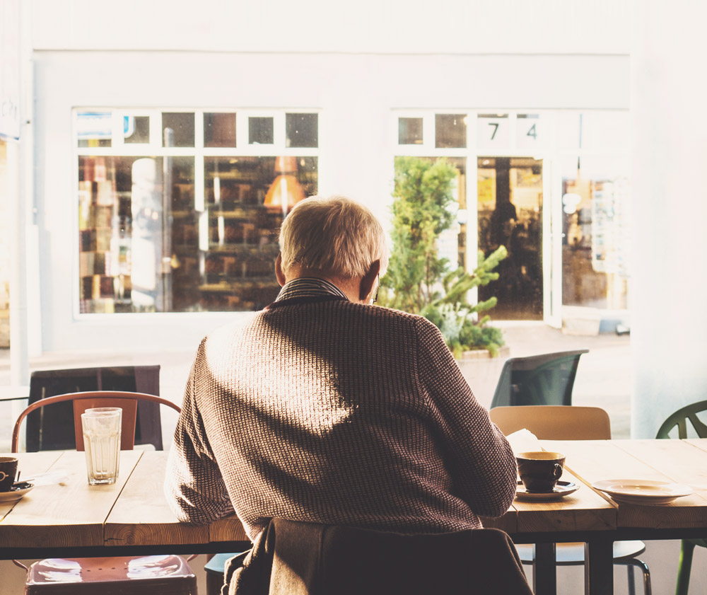 Older man sitting alone in a cafe